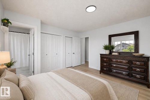 Spacious room featuring light wood-finish flooring, multiple bifold closet doors, and a full bathroom with a shower - 2803 12 Street Nw, Edmonton, AB - Indoor Photo Showing Bedroom