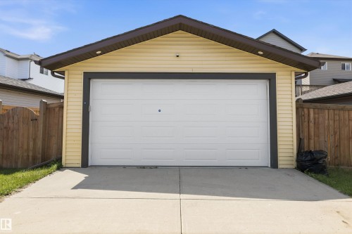 Detached garage featuring a white panel door, light yellow siding, and dark brown trim and soffit - 2803 12 Street Nw, Edmonton, AB - Outdoor With Exterior