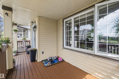 Covered porch with wood-finish flooring, light-colored siding, multiple grid-pattern windows, and a black exterior wall lantern - 2803 12 Street Nw, Edmonton, AB - Outdoor With Deck Patio Veranda With Exterior