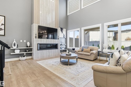 Living area featuring a fireplace, a high ceiling, and light wood-style flooring - 3167 Cameron Heights Way Nw, Edmonton, AB - Indoor Photo Showing Living Room With Fireplace