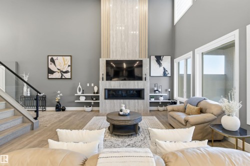 Living room featuring a towering ceiling, wood finished floors, stairs, and a fireplace - 3167 Cameron Heights Way Nw, Edmonton, AB - Indoor Photo Showing Living Room With Fireplace