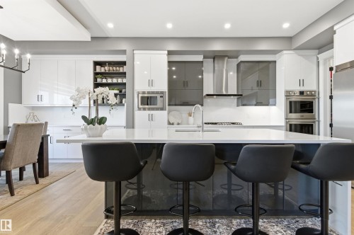Kitchen with decorative light fixtures, modern cabinets, white cabinetry, light wood-type flooring, and stainless steel appliances - 3167 Cameron Heights Way Nw, Edmonton, AB - Indoor Photo Showing Kitchen With Upgraded Kitchen