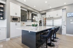Kitchen with white cabinets, modern cabinets, a breakfast bar, built in appliances, and recessed lighting - 