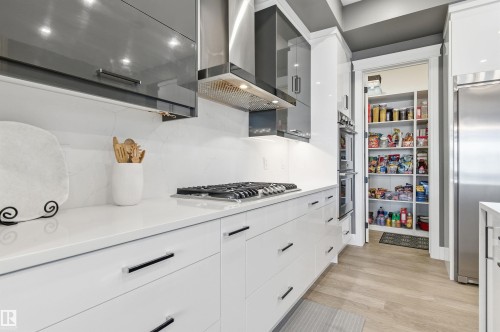 Kitchen featuring wall chimney exhaust hood, white cabinetry, modern cabinets, and stainless steel appliances - 3167 Cameron Heights Way Nw, Edmonton, AB - Indoor Photo Showing Kitchen With Upgraded Kitchen