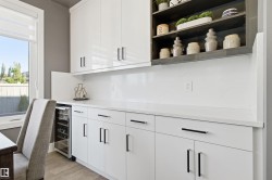 Indoor dry bar with open shelves, white cabinetry, light wood-type flooring, beverage cooler, and light stone countertops - 