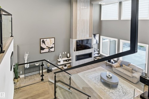 Living area with light wood-type flooring, a fireplace, and a high ceiling - 3167 Cameron Heights Way Nw, Edmonton, AB - Indoor