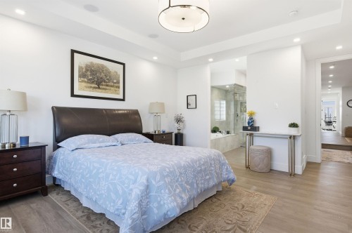 Bedroom featuring light wood-type flooring, a tray ceiling, recessed lighting, and ensuite bath - 3167 Cameron Heights Way Nw, Edmonton, AB - Indoor Photo Showing Bedroom