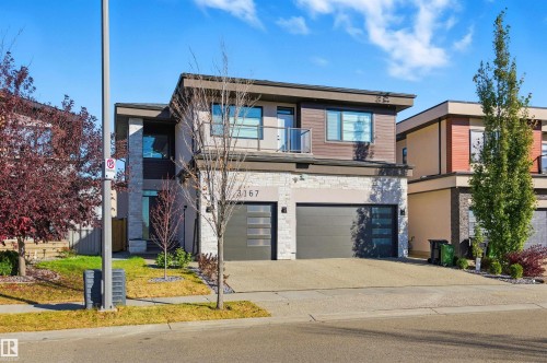 Contemporary house with stone siding, a balcony, concrete driveway, and a garage - 3167 Cameron Heights Way Nw, Edmonton, AB - Outdoor With Balcony