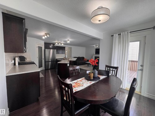 Open concept living space featuring dark hardwood flooring throughout, a kitchen with dark cabinetry and stainless steel appliances, and a dining area - 1115 61 Street Sw, Edmonton, AB - Indoor Photo Showing Dining Room