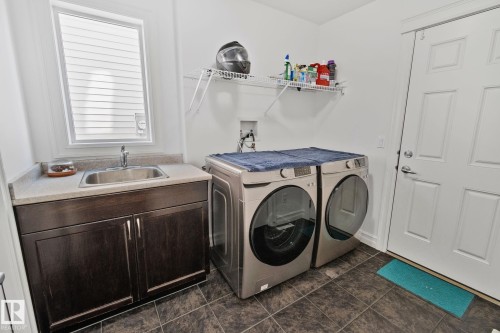 The property features a dedicated laundry area with durable floor tiling and a window for natural light - 1115 61 Street Sw, Edmonton, AB - Indoor Photo Showing Laundry Room