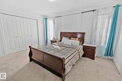 Carpeted room with white walls, featuring a window dressed with sheer and opaque curtains, and a built-in closet with bifold doors - 1115 61 Street Sw, Edmonton, AB - Indoor Photo Showing Bedroom