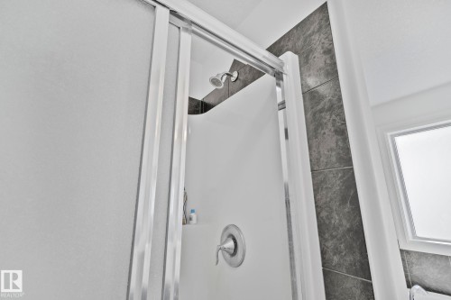 The shower features a sliding glass door, a wall-mounted shower head, and a chrome-finished faucet - 1115 61 Street Sw, Edmonton, AB - Indoor Photo Showing Bathroom