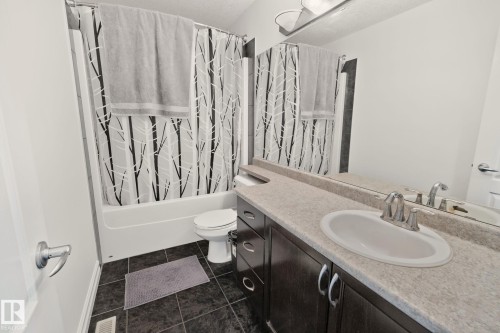 The bathroom features a vanity with dark wood cabinetry, a light-colored countertop, and an integrated sink with a chrome faucet - 1115 61 Street Sw, Edmonton, AB - Indoor Photo Showing Bathroom