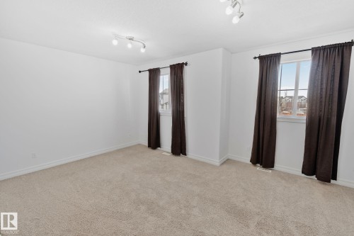 Spacious room featuring light-colored carpeting, white walls, and two windows allowing for natural light - 1115 61 Street Sw, Edmonton, AB - Indoor Photo Showing Other Room