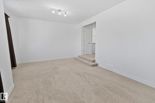 This bright room features a light-colored carpet, white walls, and a track lighting fixture on the ceiling - 1115 61 Street Sw, Edmonton, AB - Indoor Photo Showing Other Room