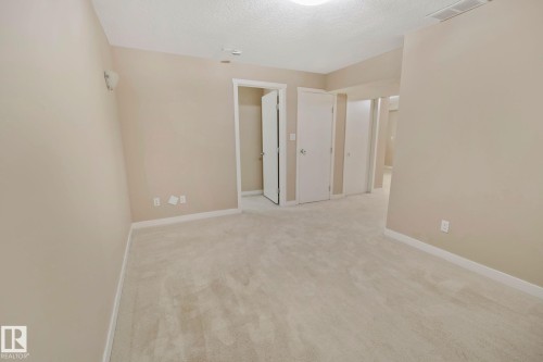 The property features an interior room with light beige walls, light-colored carpet, and white trim - 1115 61 Street Sw, Edmonton, AB - Indoor Photo Showing Other Room