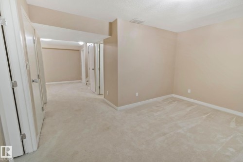 Spacious interior room featuring light-colored carpet flooring and neutral painted walls - 1115 61 Street Sw, Edmonton, AB - Indoor Photo Showing Other Room