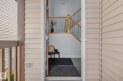Light-colored siding exterior with a wood-finish porch railing - 1115 61 Street Sw, Edmonton, AB - Outdoor With Exterior