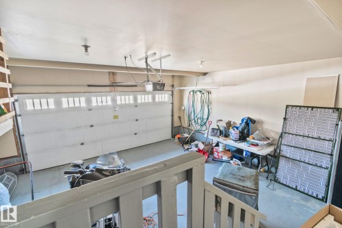 The property includes a spacious garage with a white sectional door featuring windows, overhead lighting, and a neutral-toned wall finish - 1115 61 Street Sw, Edmonton, AB - Indoor Photo Showing Garage