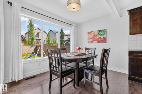 Bright dining area featuring a large window, wood-finish flooring, and a contemporary ceiling light fixture - 1115 61 Street Sw, Edmonton, AB - Indoor Photo Showing Dining Room