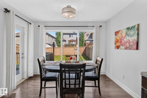 Dining area featuring wood-finish flooring, a contemporary ceiling light fixture, and a sliding glass door providing access to the backyard - 1115 61 Street Sw, Edmonton, AB - Indoor Photo Showing Dining Room