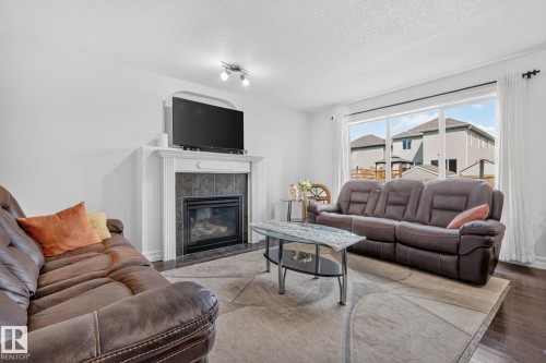 Living area featuring a fireplace with a dark tile surround and white mantel - 1115 61 Street Sw, Edmonton, AB - Indoor Photo Showing Living Room With Fireplace
