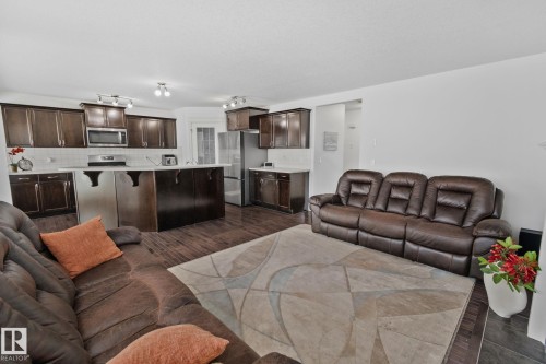 Open concept living area featuring dark wood flooring, an island kitchen with dark cabinetry, and white countertops - 1115 61 Street Sw, Edmonton, AB - Indoor