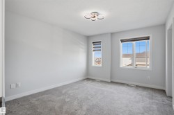 Carpeted room featuring a contemporary ceiling light fixture, two windows with blinds, light gray wall paint, and white baseboards - 