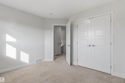 Neutral-toned carpeting extends throughout this room, featuring a pair of white five-panel doors with contemporary hardware - 