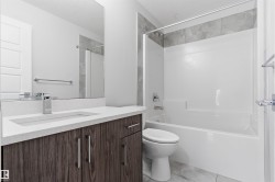 Bathroom featuring a single vanity with wood-finish cabinetry, a white countertop, and an integrated rectangular sink - 