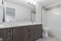 Bathroom featuring a dual vanity with a light countertop, wood-finish cabinetry, and chrome hardware - 