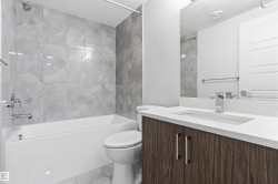 Bathroom featuring a wood-finish vanity with a white countertop and integrated sink, chrome faucet, and full-width mirror - 