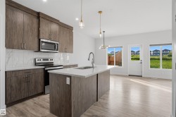 Kitchen featuring wood-finish cabinetry, stainless steel appliances, a white tile backsplash, and a central island with a sink and modern faucet - 