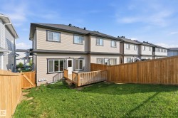 Private backyard featuring a wooden fence, green lawn, and a wooden deck with railing - 