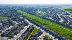 Extensive residential development featuring numerous single-family homes and townhomes with dark shingle roofs - 