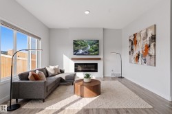 Spacious living area featuring expansive windows, a modern electric fireplace with a wood-finish mantel, and light wood-finish flooring - 