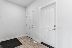 Entryway featuring wood-finish flooring, white baseboards, and a modern door with multiple square windows - 