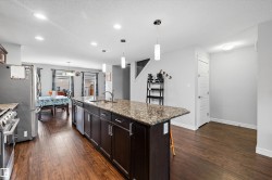 Kitchen island featuring a granite-style countertop, undermount sink, and pendant lighting - 