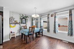Dining area featuring wood-finish flooring, two large windows, and a contemporary ceiling light fixture - 