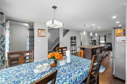Spacious dining area featuring wood-finish flooring and a contemporary pendant light fixture - 