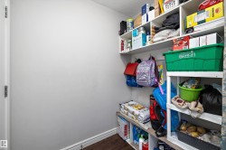 Pantry featuring built-in white shelving, wood-finish flooring, and white baseboards - 