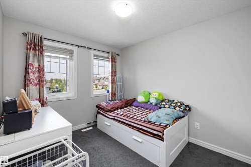 Light-filled interior space with two windows featuring white frames and grid patterns - 1563 Tamarack Boulevard Nw, Edmonton, AB - Indoor Photo Showing Bedroom
