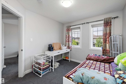 Bedroom featuring light gray wall paint, dark gray carpeting, and two windows with white trim - 1563 Tamarack Boulevard Nw, Edmonton, AB - Indoor Photo Showing Bedroom