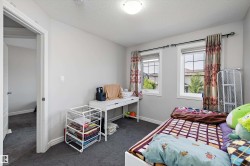 Bedroom featuring light gray wall paint, dark gray carpeting, and two windows with white trim - 