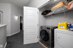 Dedicated laundry area featuring a front-load washing machine, a white dryer, and an overhead wire shelving unit - 