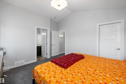 Bedroom featuring vaulted ceilings, plush grey carpeting, and white trim - 