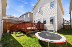 Spacious backyard featuring a wooden deck with railing, stairs, and a ground-level planter box - 