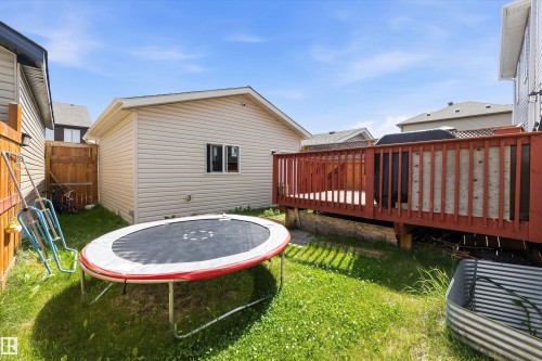 Expansive backyard featuring a wood deck with red-stained railings, a separate structure with vinyl siding and a window, and a wood privacy fence - 1563 Tamarack Boulevard Nw, Edmonton, AB - Outdoor With Deck Patio Veranda With Exterior