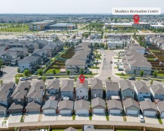 Aerial view showcasing a residential street with attached garages and a community recreation center in the distance - 