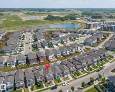 Aerial view of a residential neighborhood featuring detached homes with grey roofs and varied exterior finishes - 